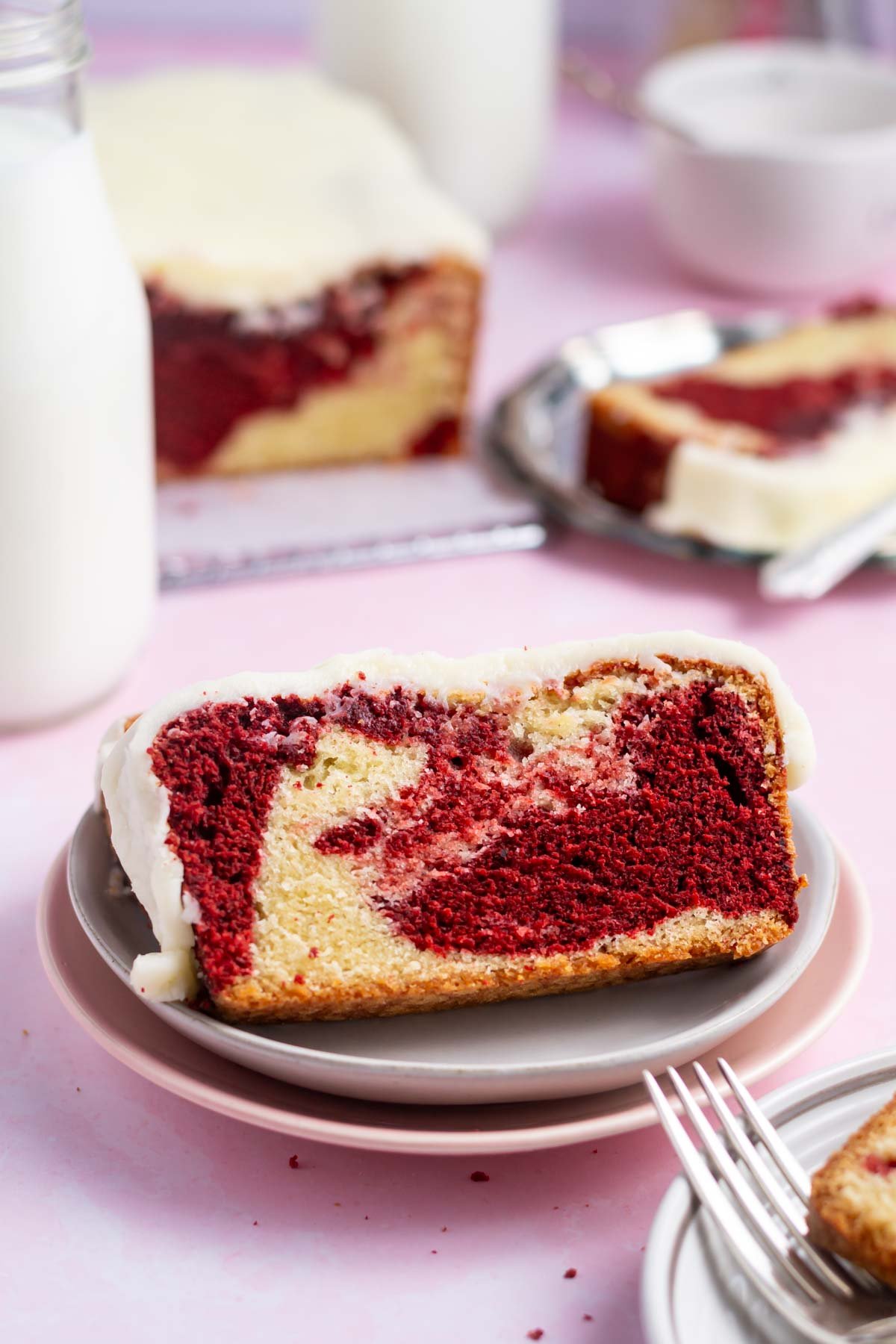 slice of red velvet loaf on a plate with the cake in the background