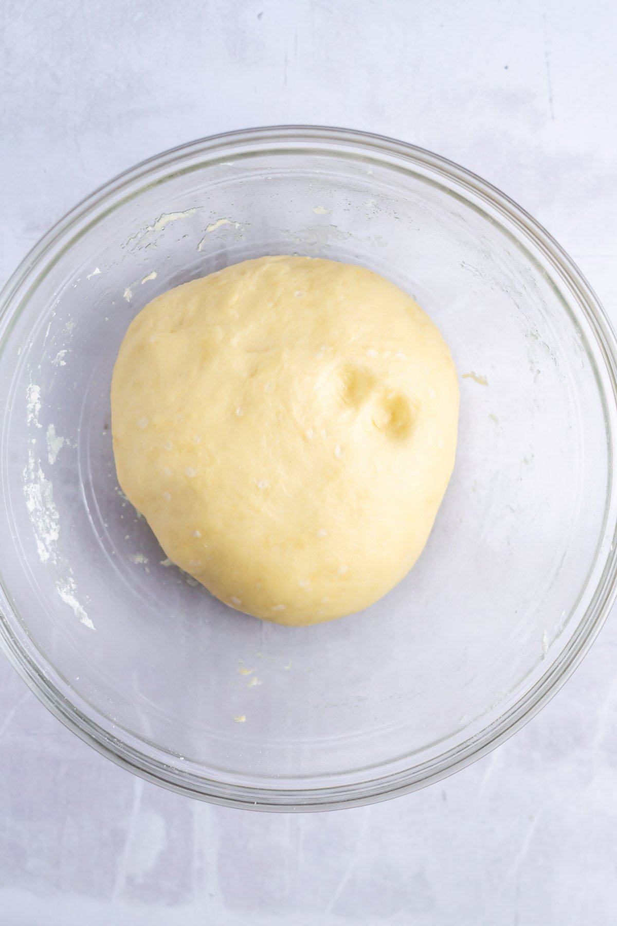 small batch cinnamon roll dough after the first rise, showing the dough holding a finger imprint