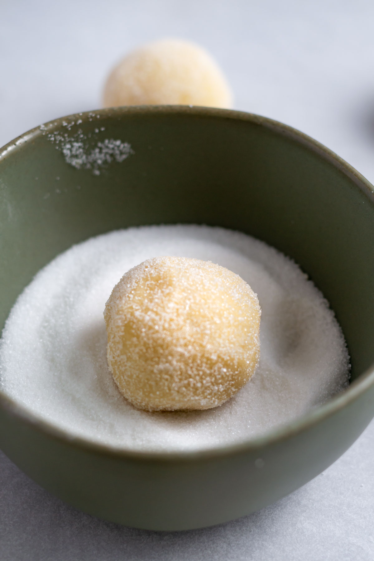 vanilla sugar cookie rolled in granulated sugar in a bowl of sugar