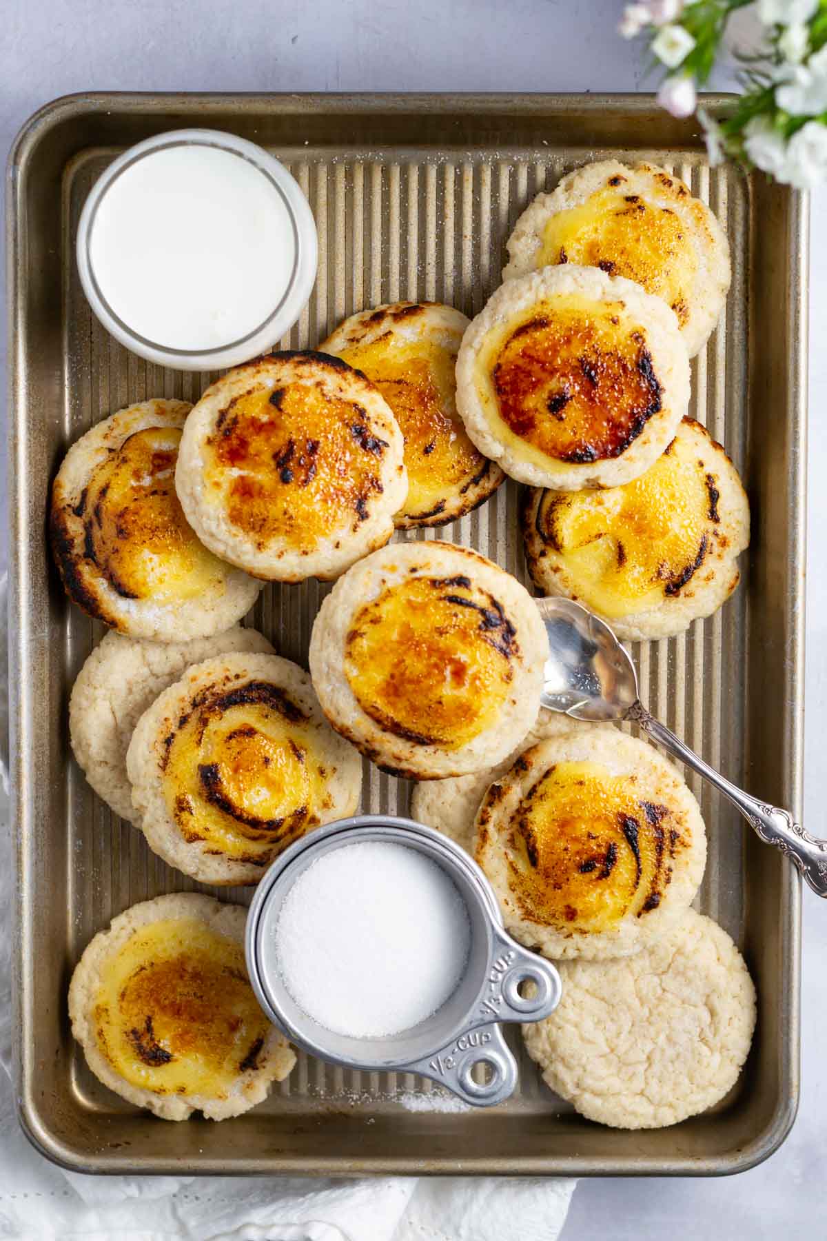 creme brulee cookies with milk and a cup of sugar on a baking pan