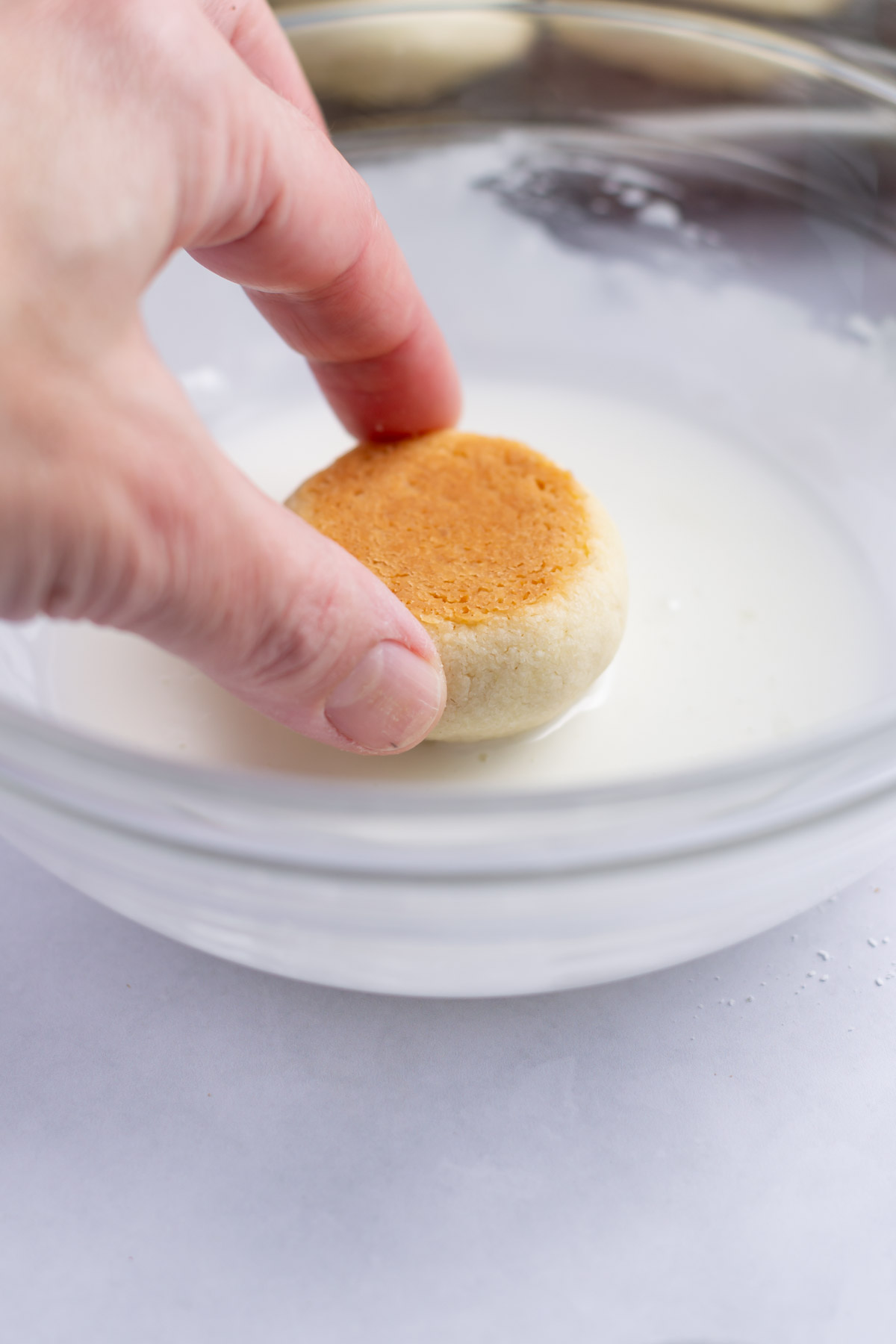 hand dipping a cookie into icing glaze