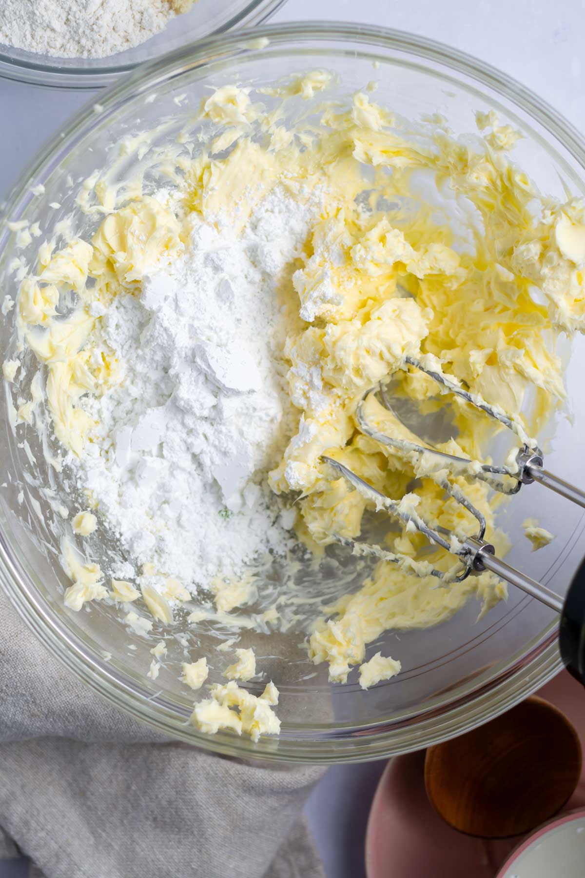 powdered sugar added to creamed butter in a bowl