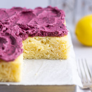lemon snack cake with blueberry frosting on a parchment lined pan with a fork