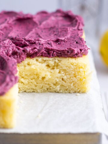 lemon snack cake with blueberry frosting on a parchment lined pan with a fork