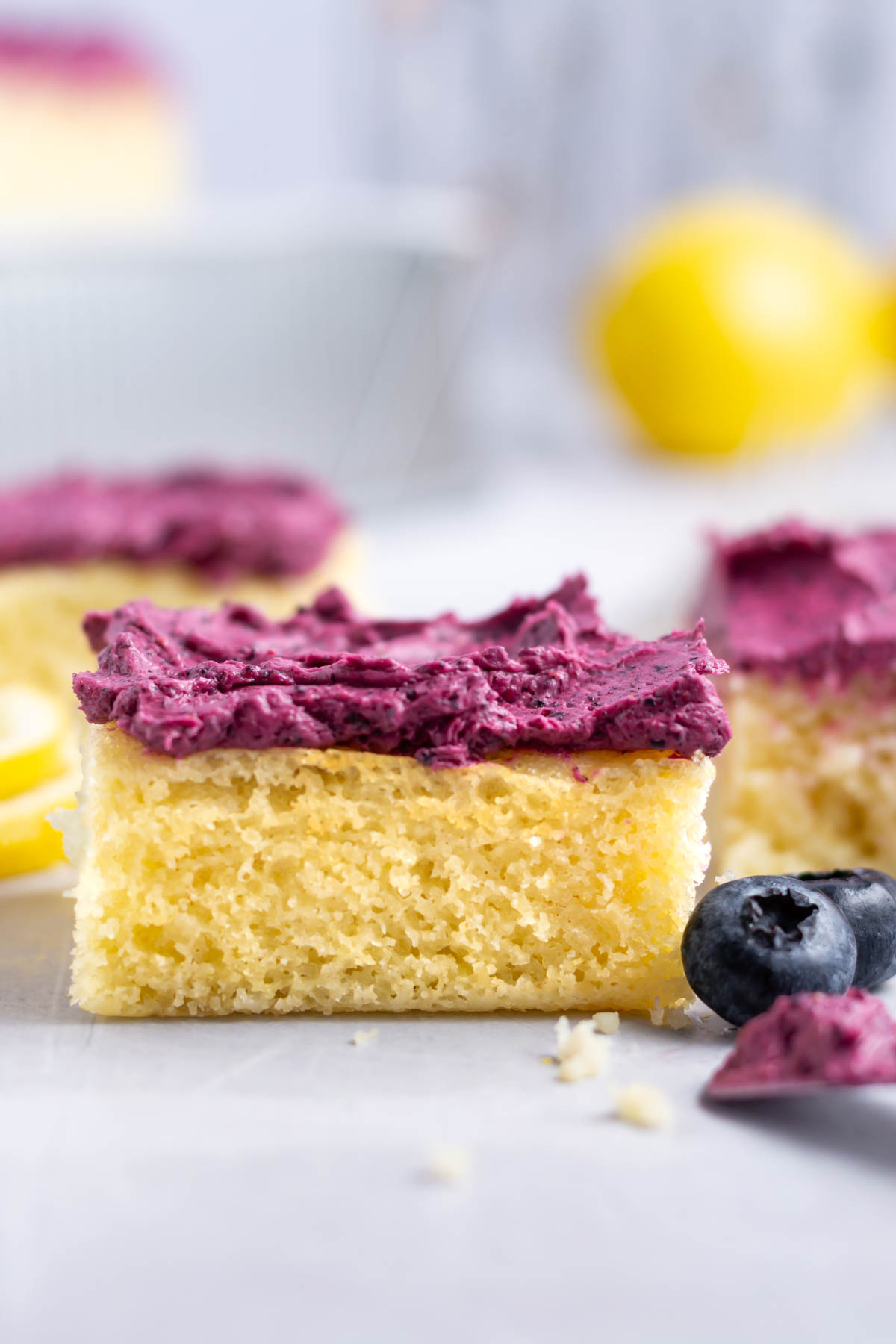 lemon cake with frosting and fresh blueberries with a lemon in the background