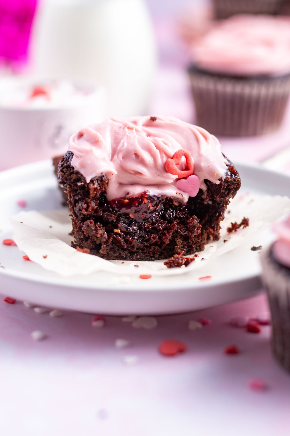 chocolate raspberry cupcake with a bite missing showing the raspberry jam filling