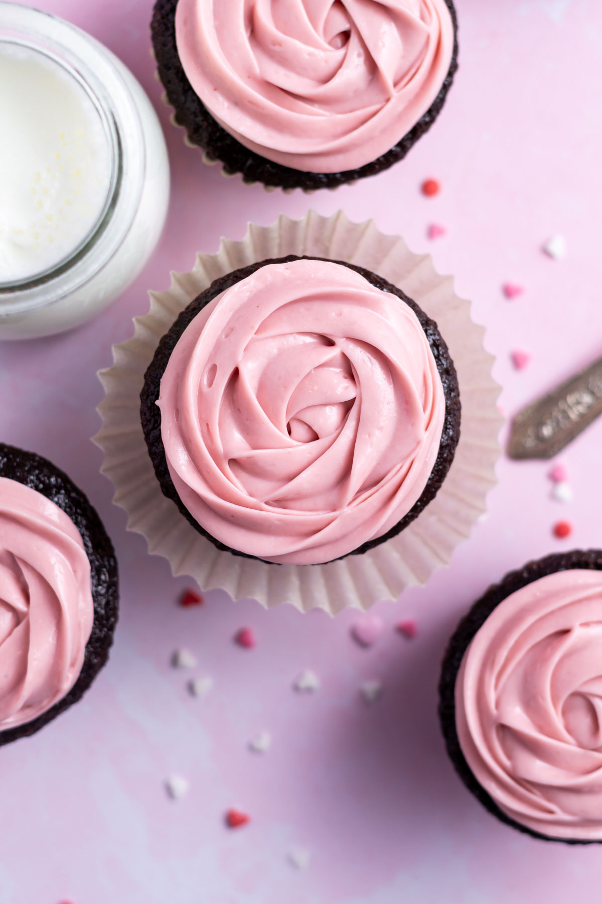 overhead look at pink chocolate ganache piped on chocolate cupcakes