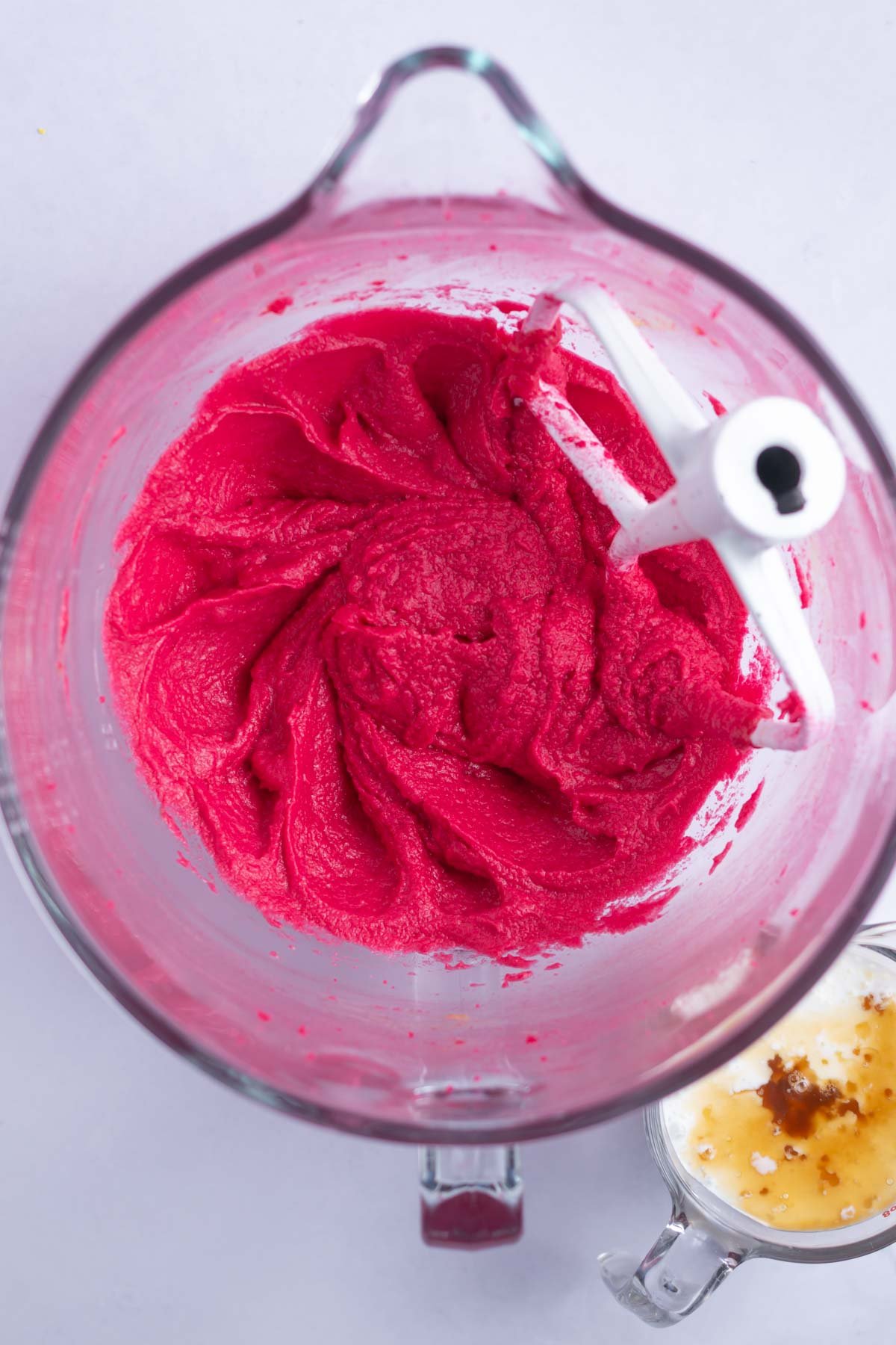very pink butter, sugar, eggs and food coloring mixed together in a mixing bowl