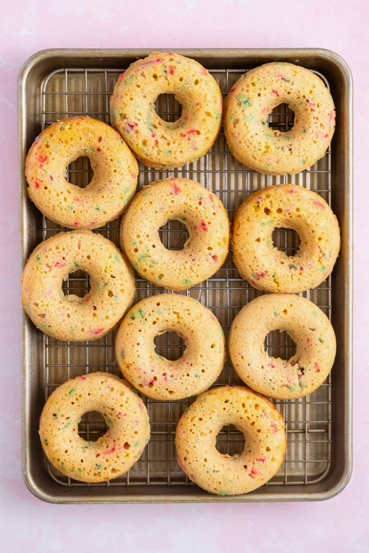 unglazed donuts on a cooling rack over a baking sheet pan.