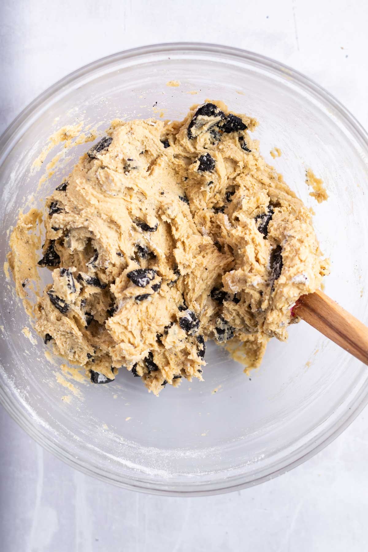 oreo cookies folded into cookie dough in a mixing bowl