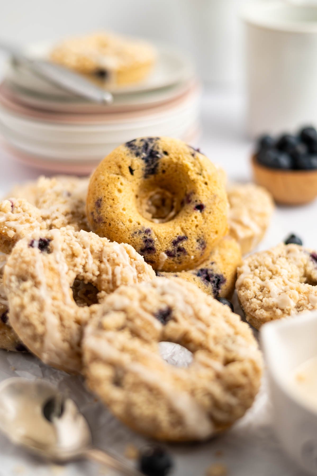pile of blueberry donuts with plates and a bowl of blueberries