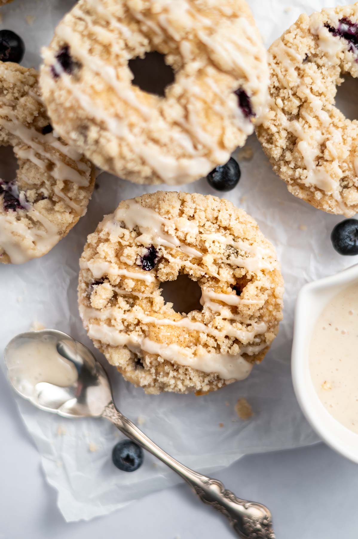 blueberry donuts with crumble and icing on a piece of parchment paper