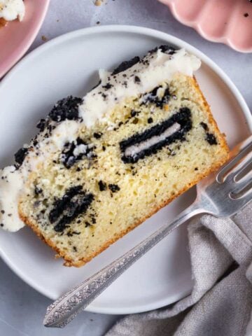 slice of oreo pound cake with vanilla cream icing on a plate with a fork