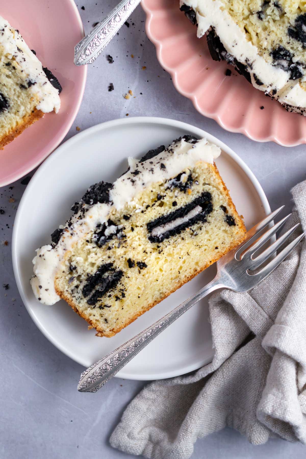 slice of oreo pound cake with vanilla cream icing on a plate with a fork