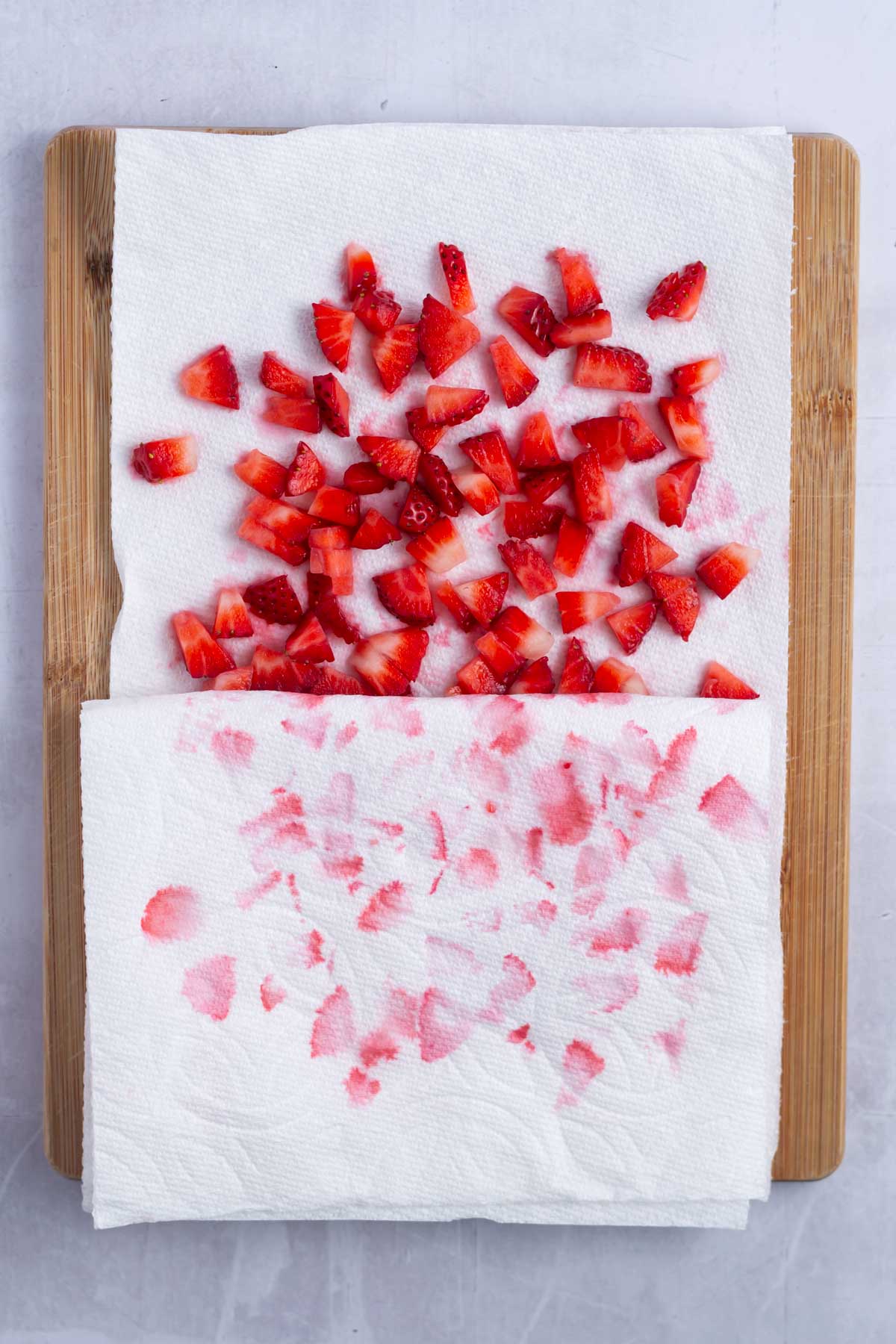 chopped strawberries on a paper towel lined cutting board