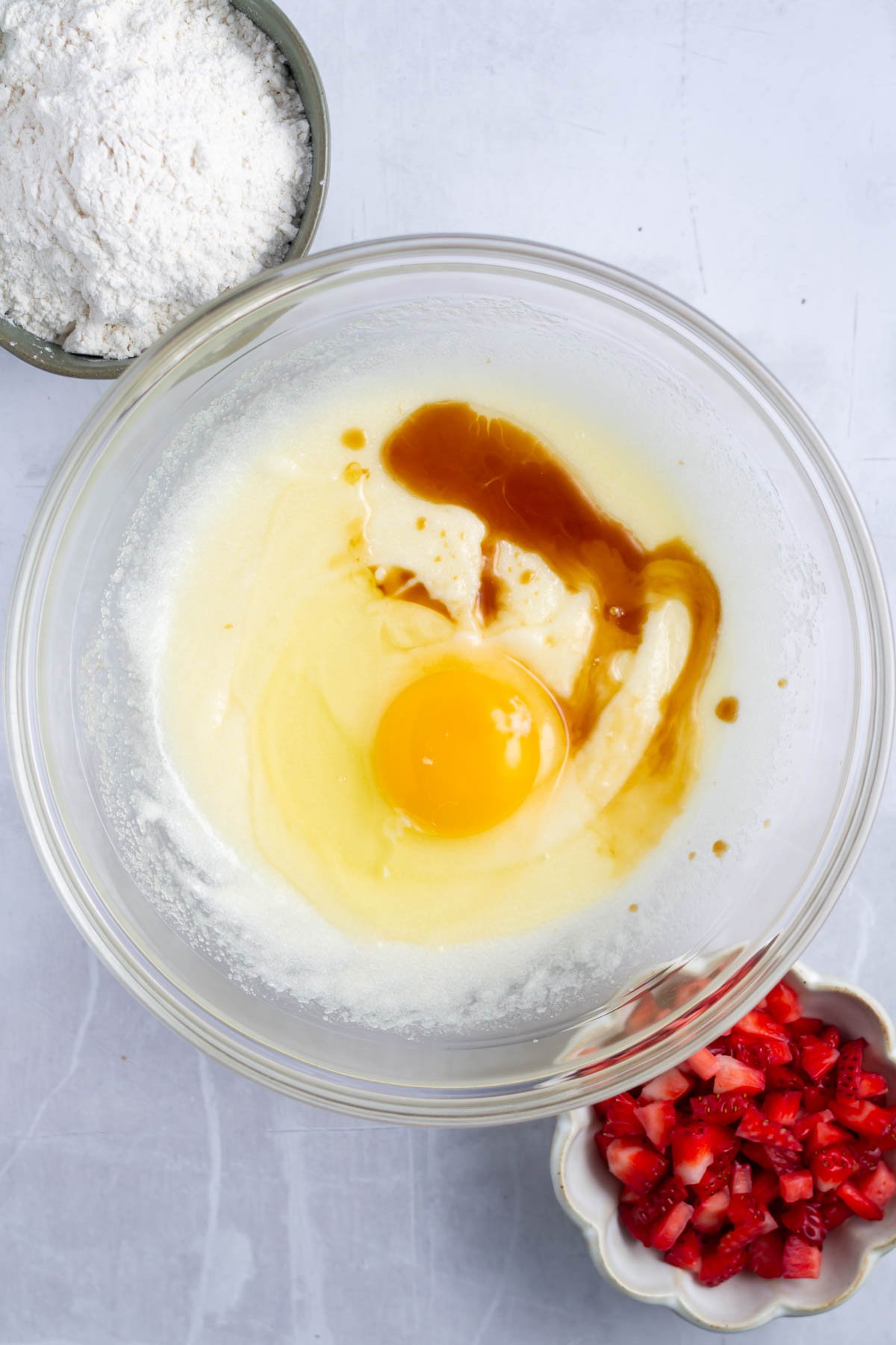 egg and vanilla added to whisked sugar and butter in a bowl