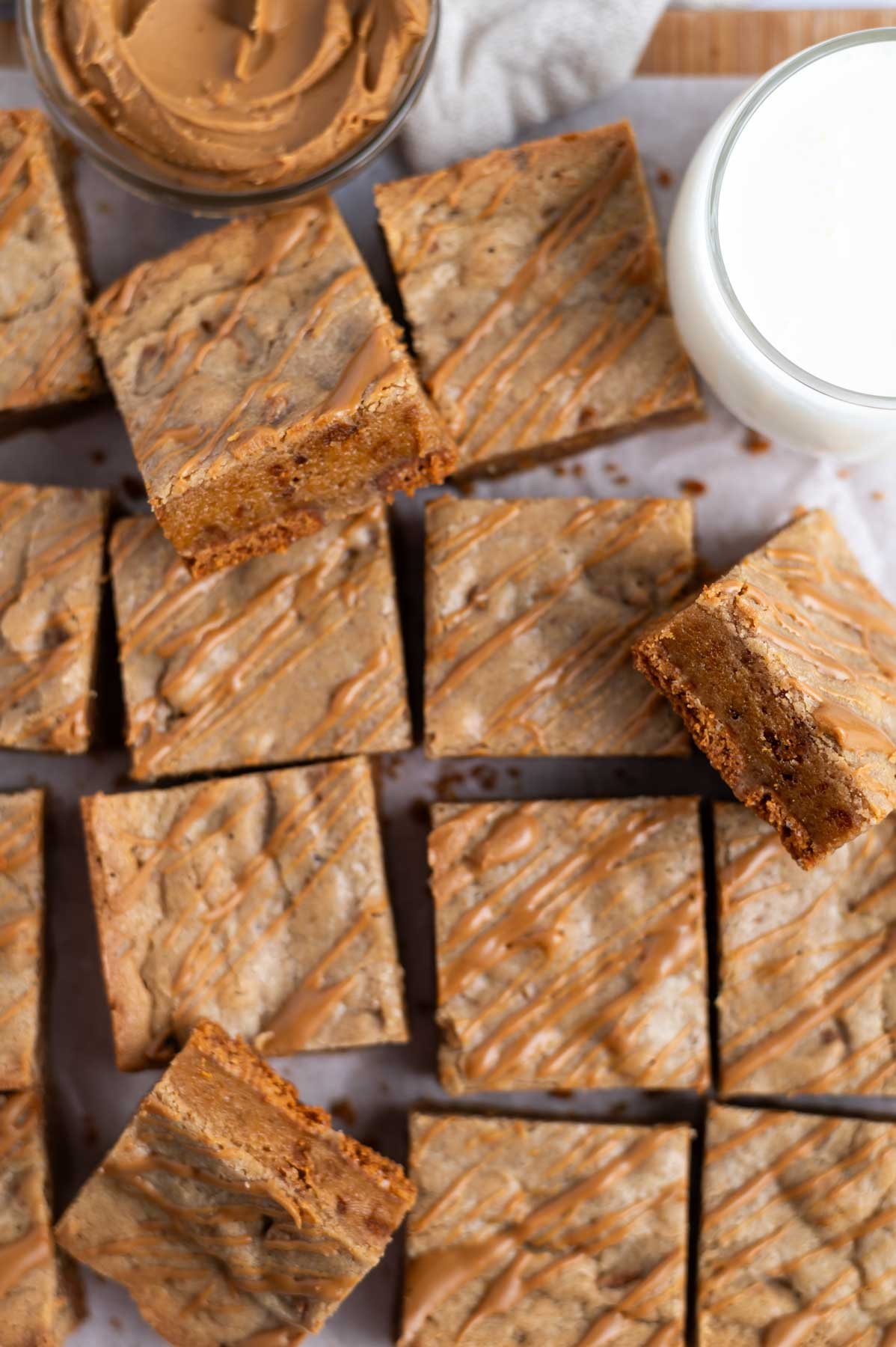 blondies on a parchment lined cutting board with milk