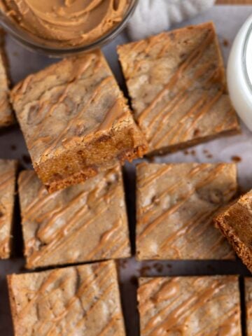 biscoff blondies showing chewy inside texture on parchment paper with a glass of milk