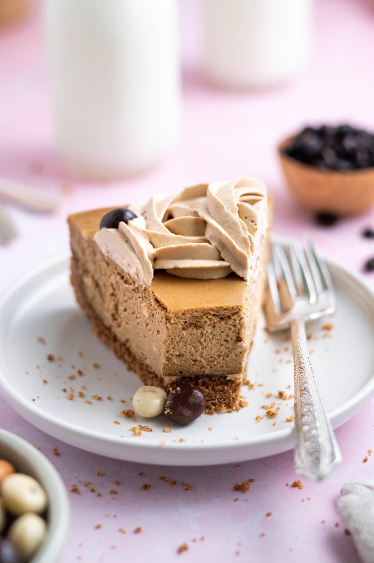 slice of espresso cheesecake on a plate with a fork and coffee beans and milk in the background