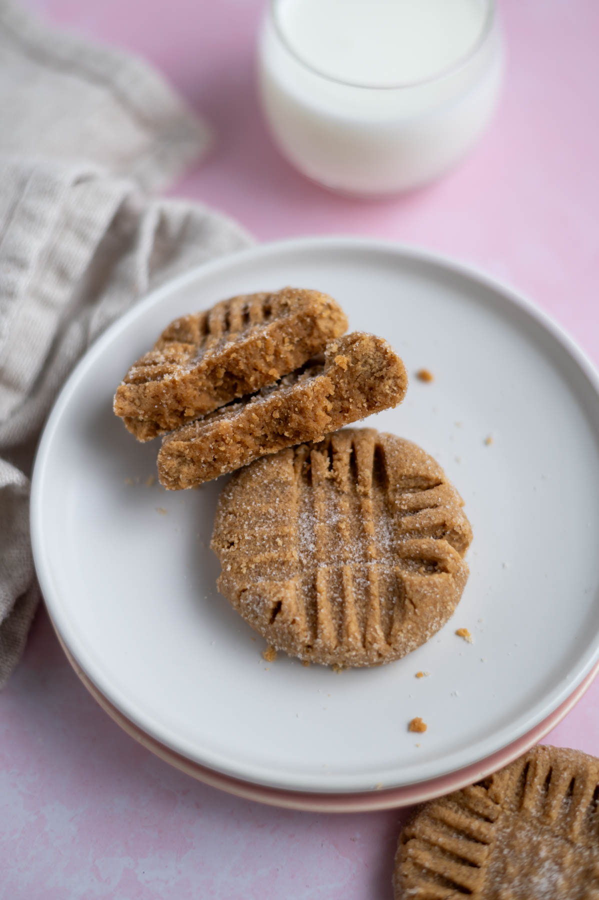 two small batch peanut butter cookies on a plate, one broken in half