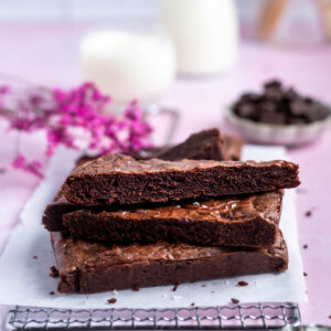 stack of brownies on a parchment lined cooling rack with milk