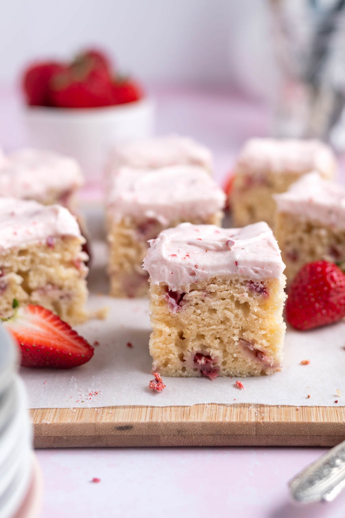 slices of strawberry snack cake on a parchment lined cutting board