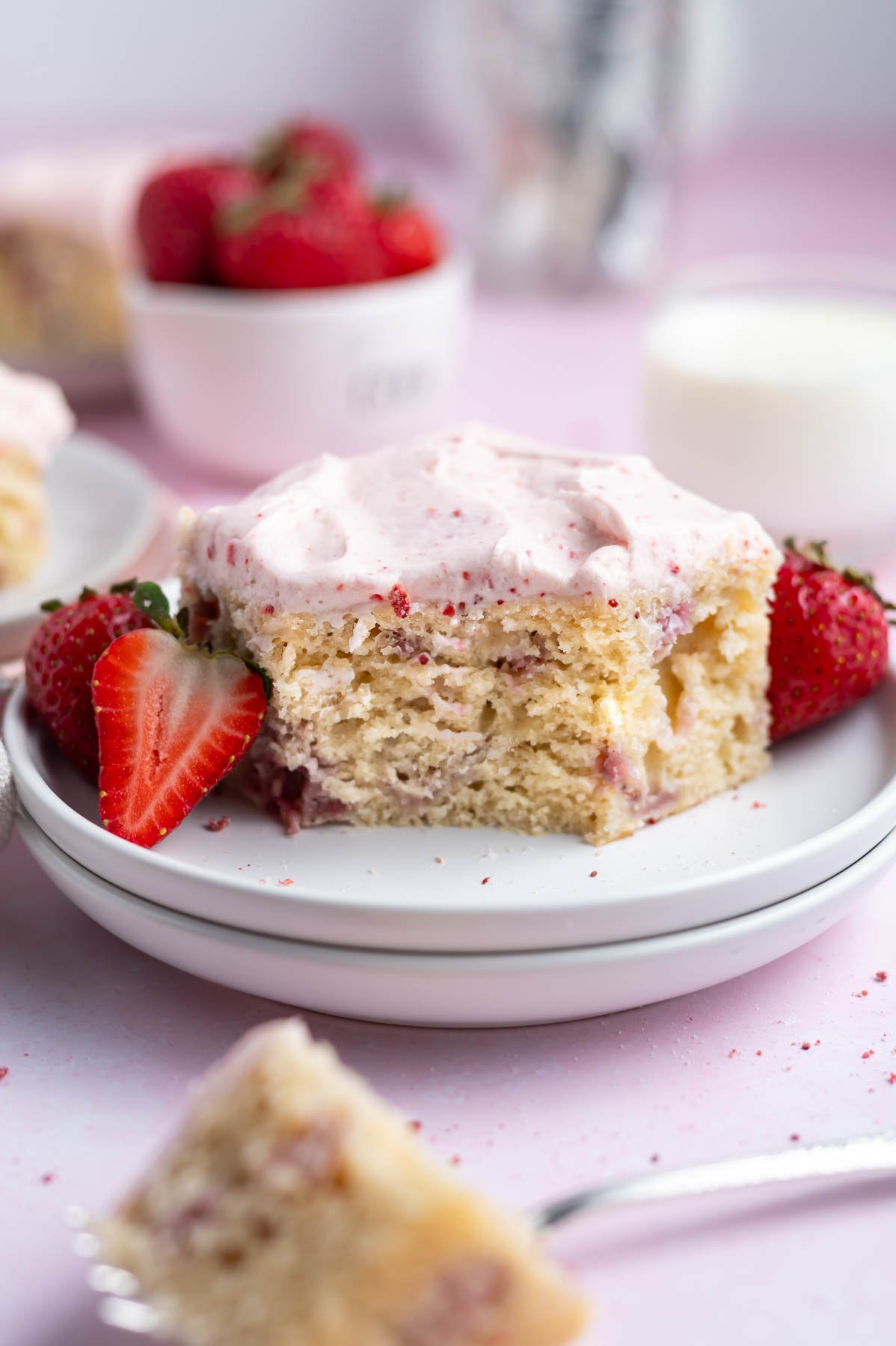 slice of strawberry snack cake with a bite missing on a plate