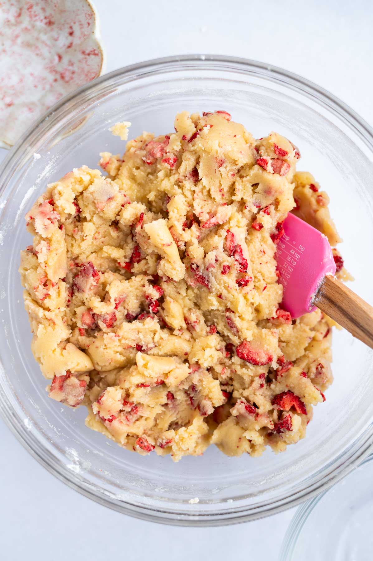 strawberry sugar cookie dough in a mixing bowl with a spatula