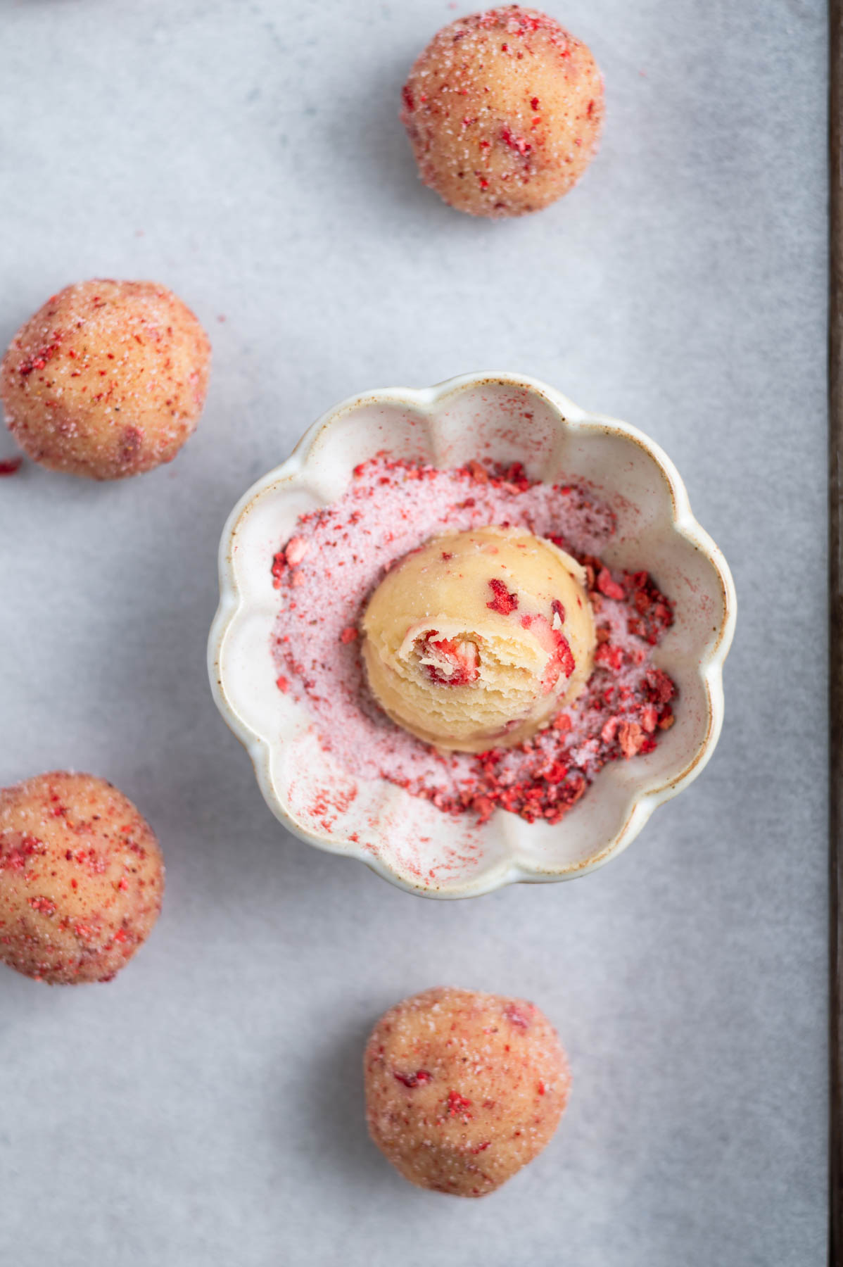 cookie dough ball in a bowl of strawberry sugar