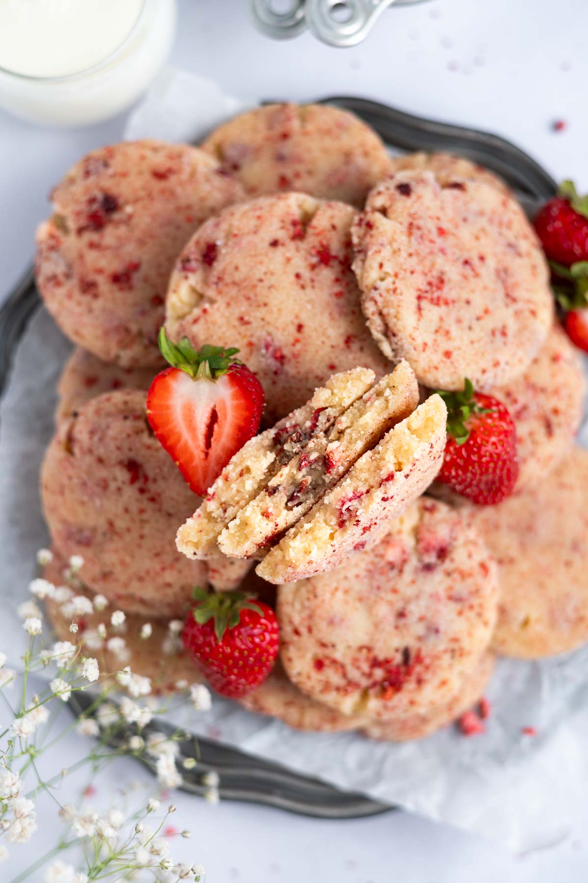 strawberry sugar cookies on a plate with a few broken open to show the soft centers