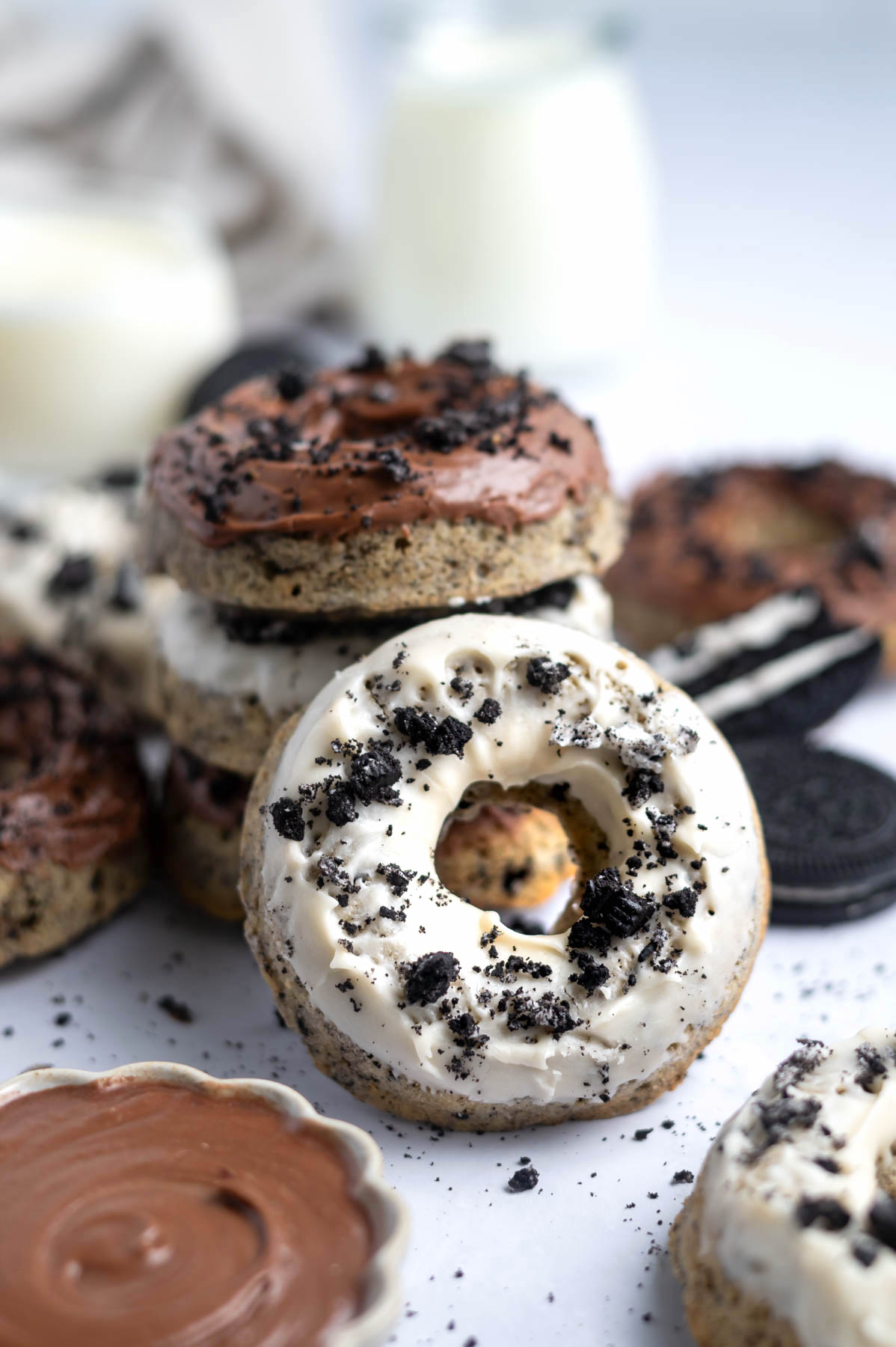 donut leaning on a stack of donuts with milk glasses in the background