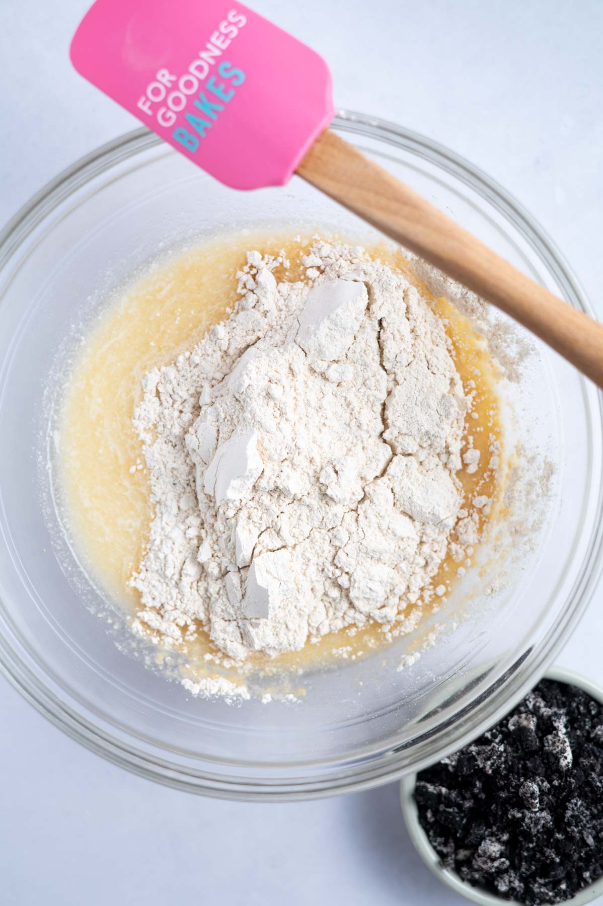 dry ingredients added to wet ingredients in a bowl with a spatula