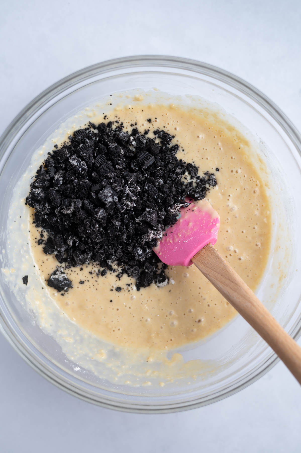 oreo cookie pieces added to donut batter in a mixing bowl