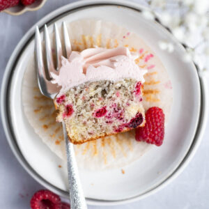 raspberry cupcake showing soft crumb interior on a plate with a fork