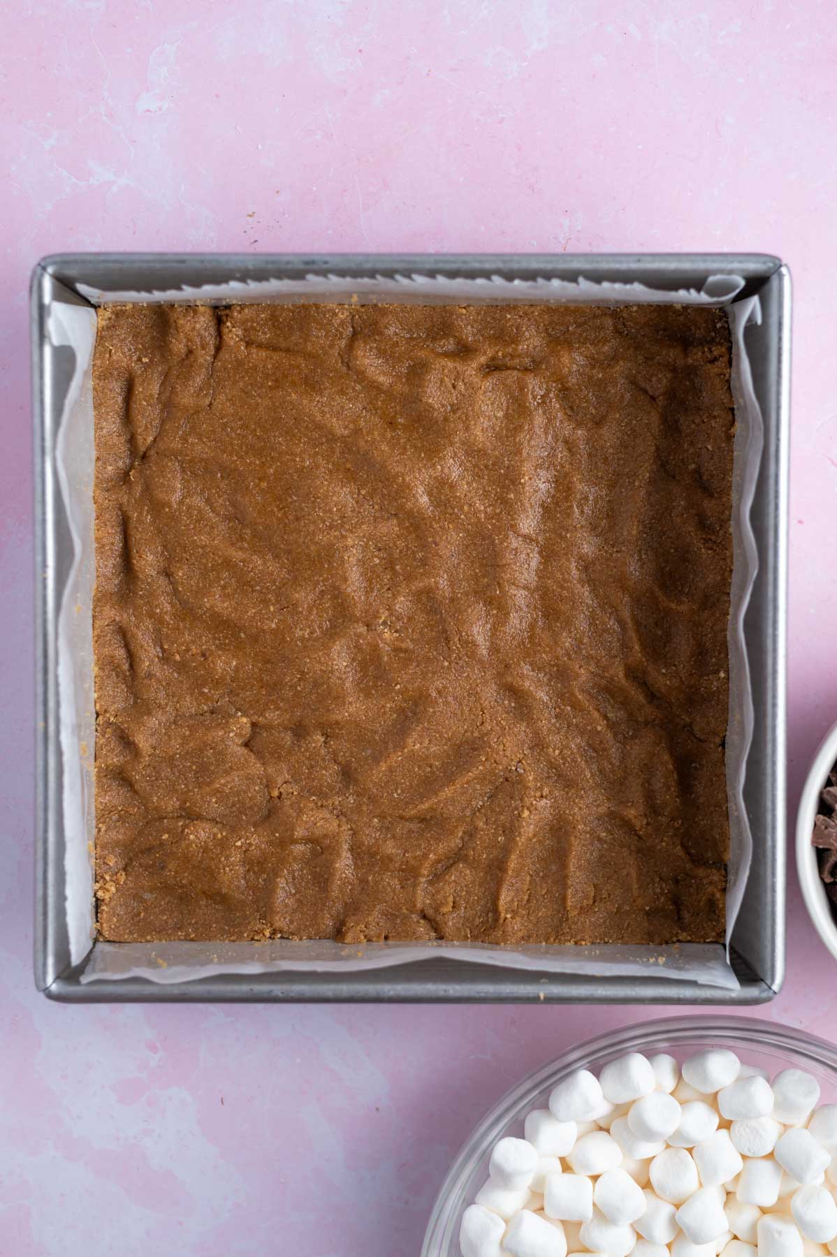 cookie dough layer pressed in the bottom of a parchment lined baking pan