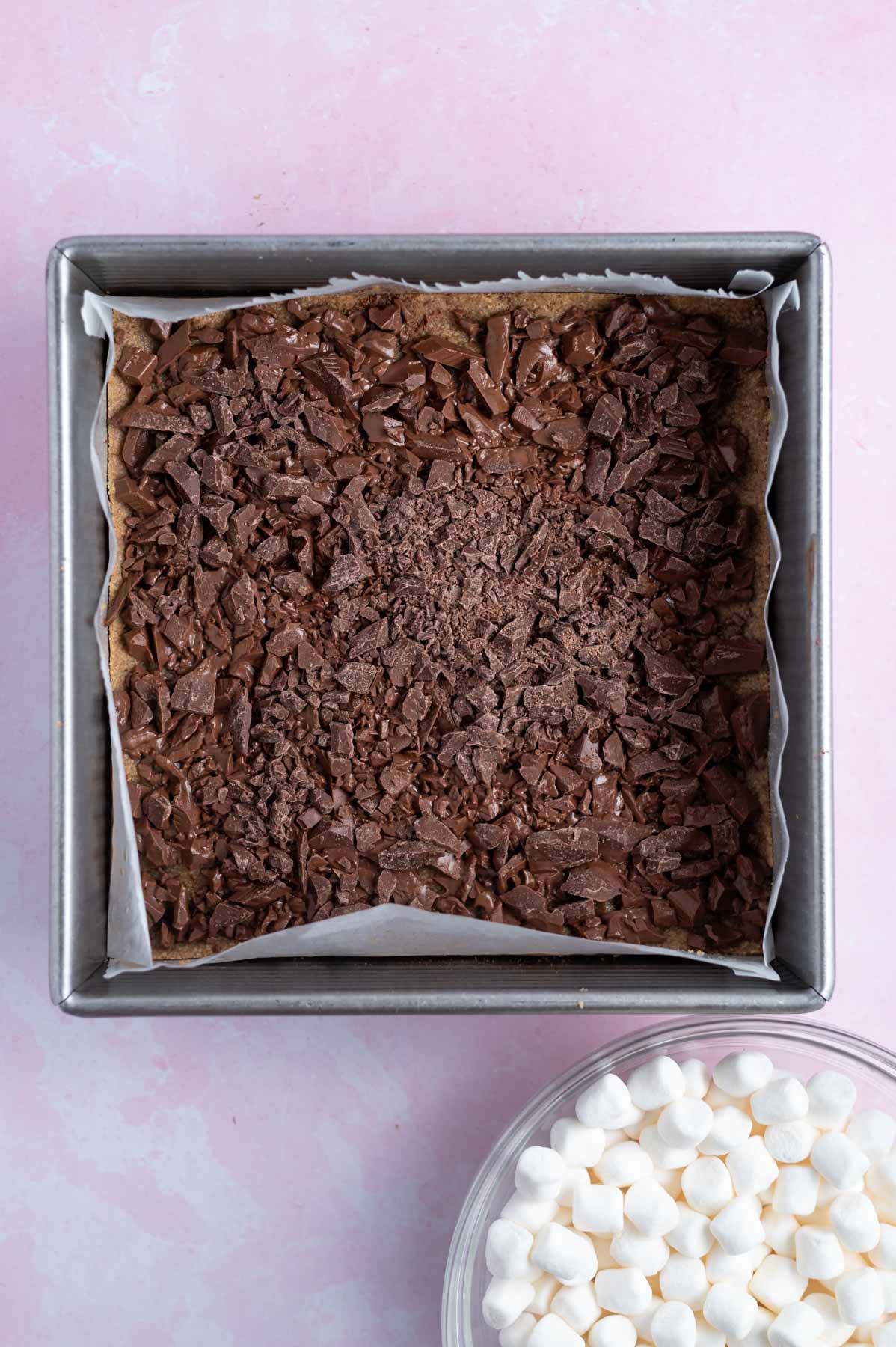 chopped milk chocolate over graham cracker layer in a baking tin