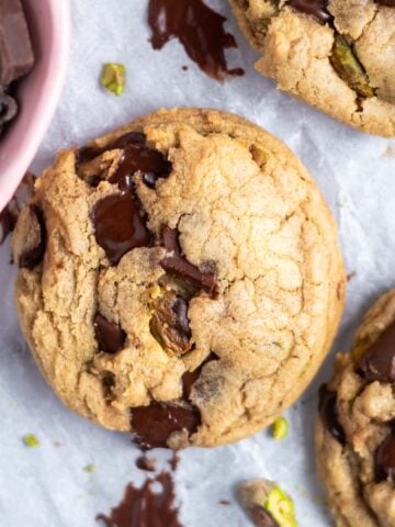 pistachio chocolate chip cookies with melty chocolate on parchment paper