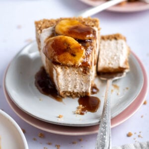 slice of bananas foster cheesecake on a plate with a bite on a fork