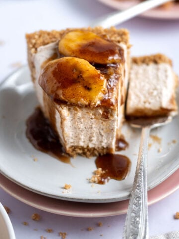 slice of bananas foster cheesecake on a plate with a bite on a fork