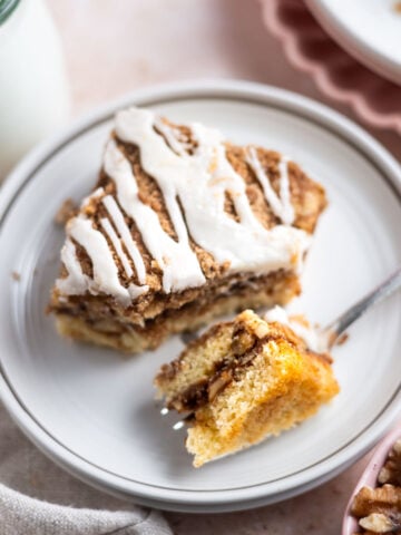 slice of cinnamon walnut coffee cake on a plate with a fork holding a bite