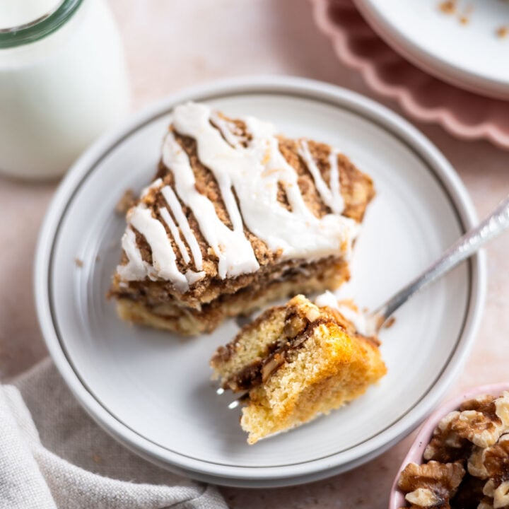 slice of cinnamon walnut coffee cake on a plate with a fork holding a bite