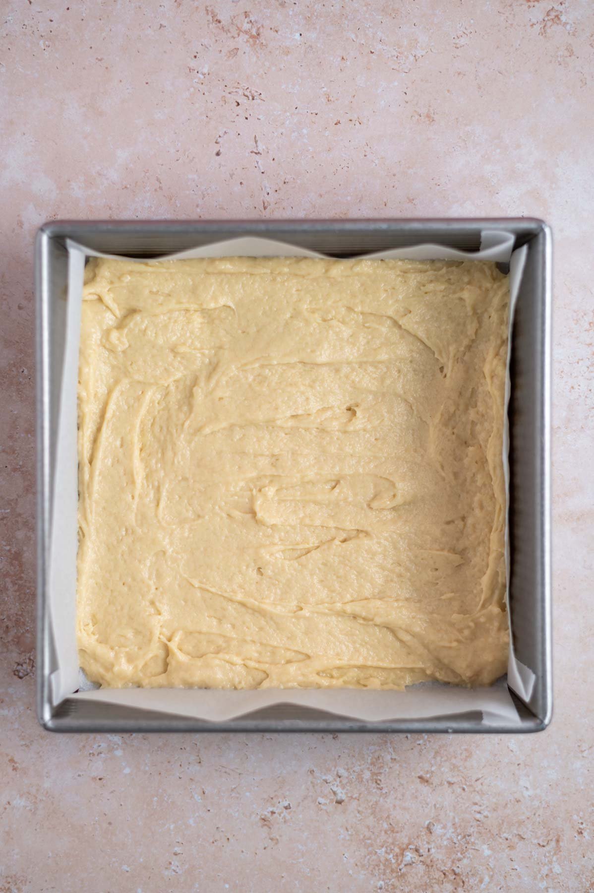 baking tin lined with parchment with a layer of cake batter