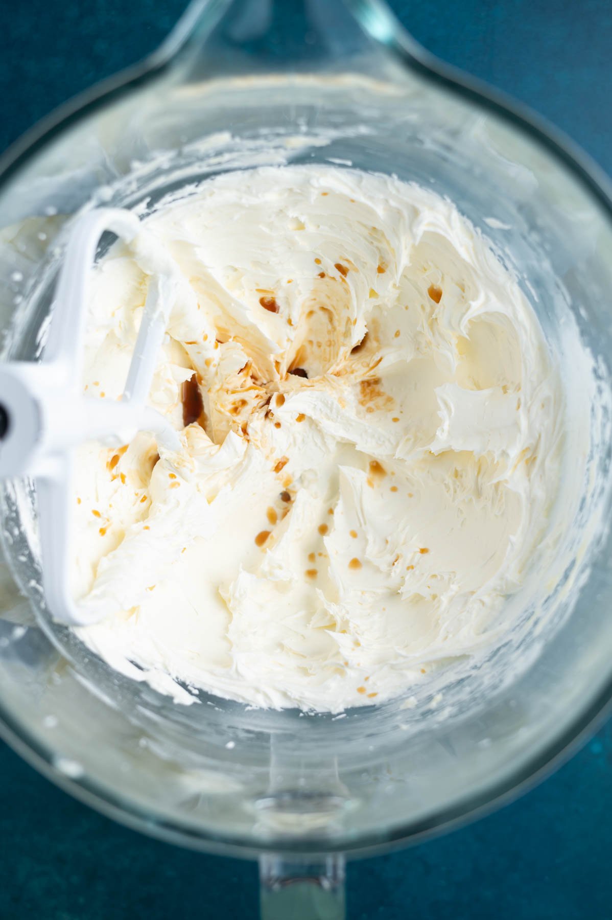 vanilla added to fluffy buttercream frosting in a mixing bowl