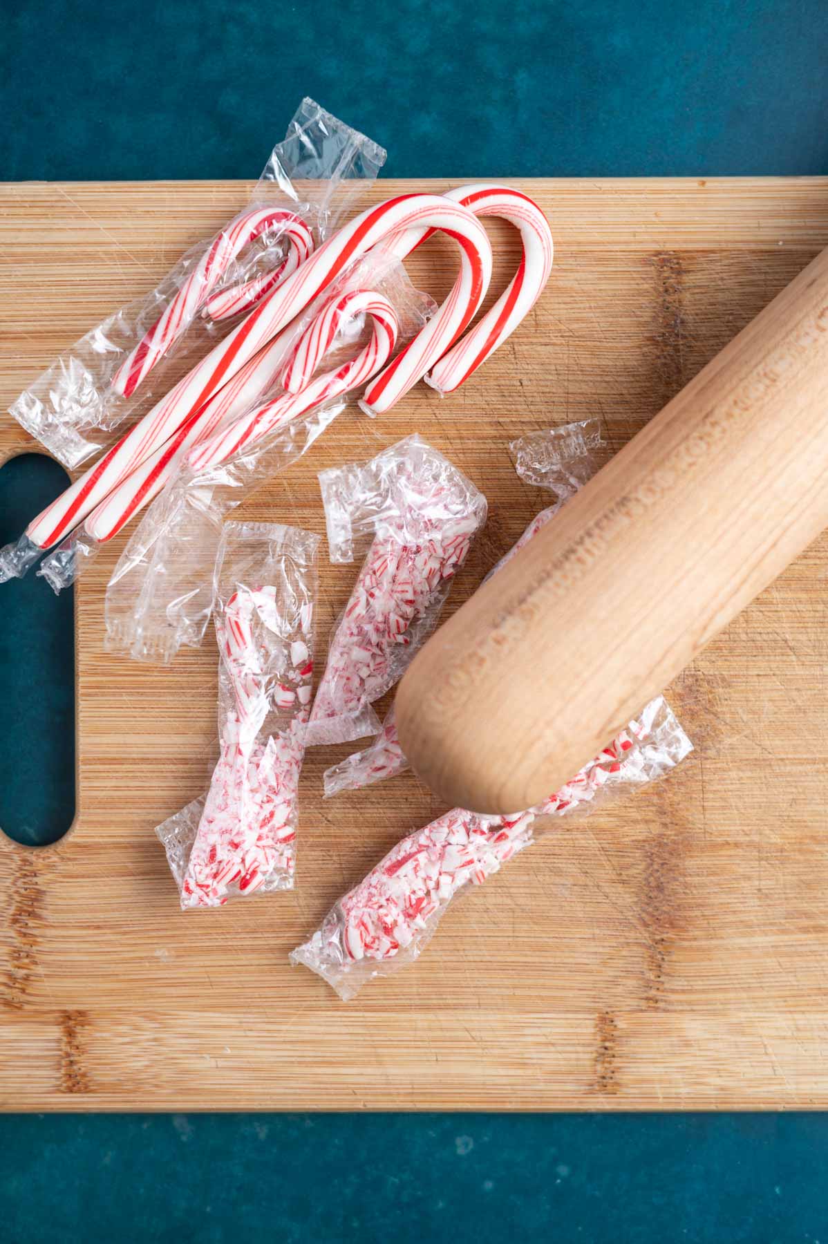 candy canes on a cutting board with a rolling pin