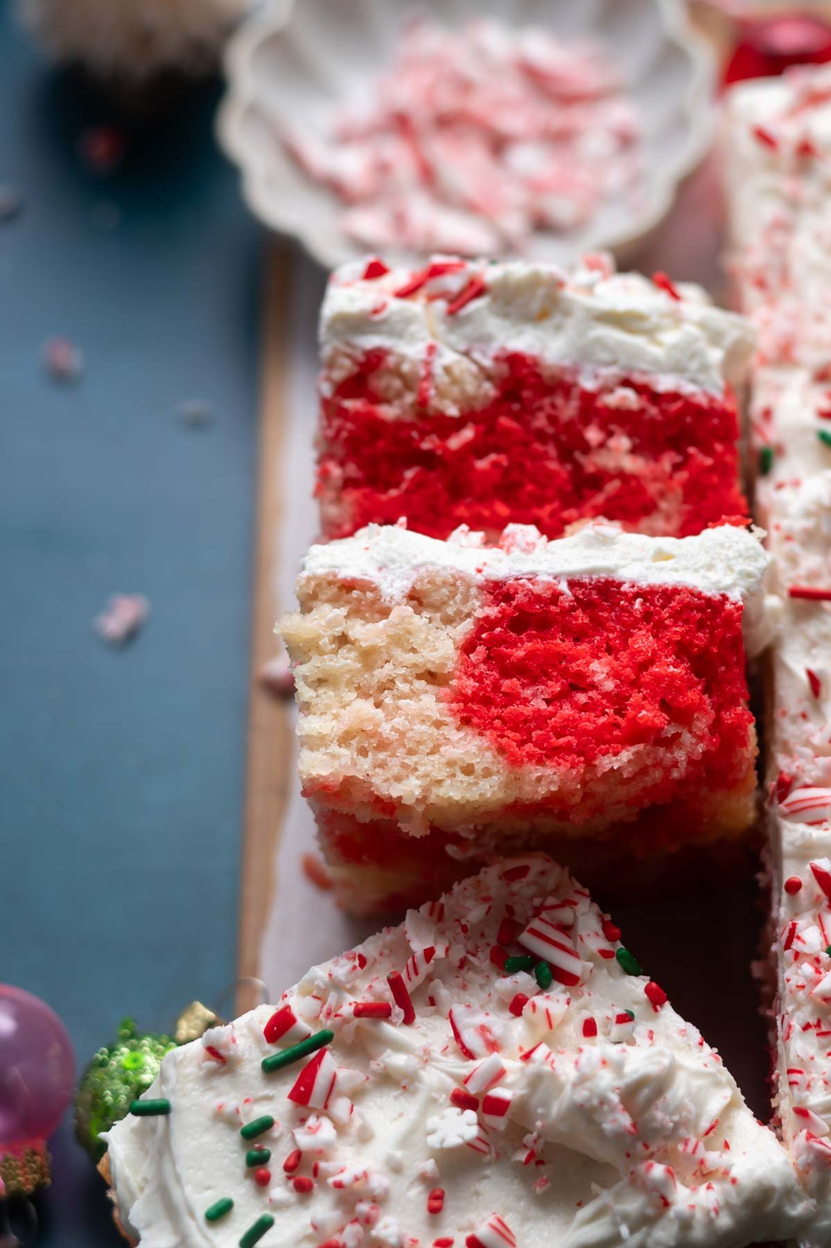 slices of cake on their sides on a parchment lined cutting board with crushed candy canes and sprinkles on top