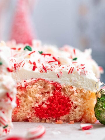 slice of candy cane cake on a cutting board showing the red swirl