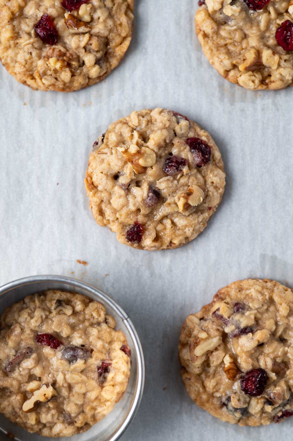 cookies on a parchment lined baking rack with a biscuit cutter "scooting" on of them