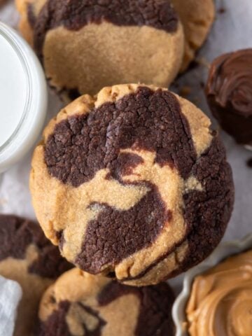 peanut butter nutella cookie with a glass of milk, spoon of nutella and bowl of peanut butter