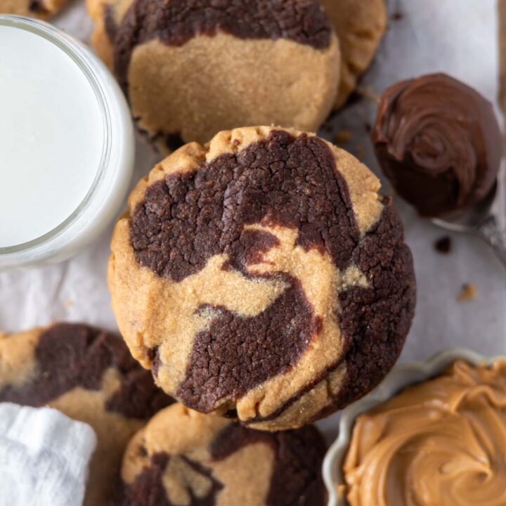 peanut butter nutella cookie with a glass of milk, spoon of nutella and bowl of peanut butter