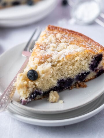 slice of blueberry ricotta cake on a plate with a fork